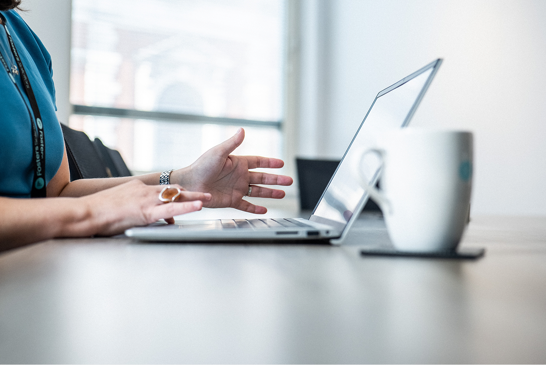 Client gesturing during a video call on a laptop at a desk