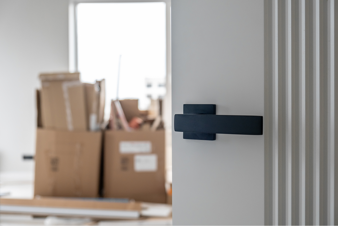 Close-up of a modern door handle with moving boxes in the background