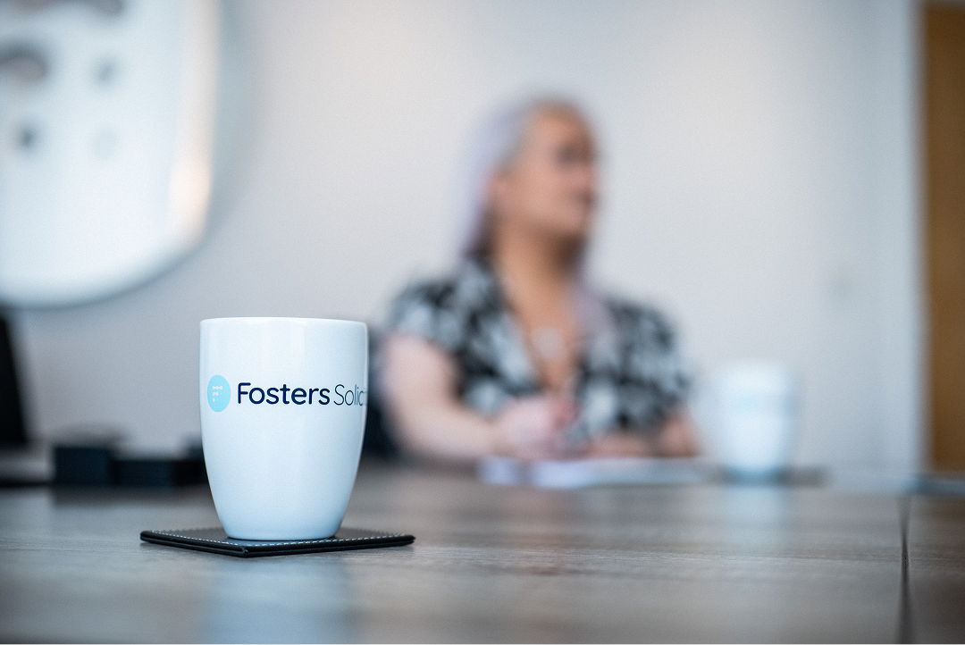 Fosters Solicitors mug on a table with a client in the background