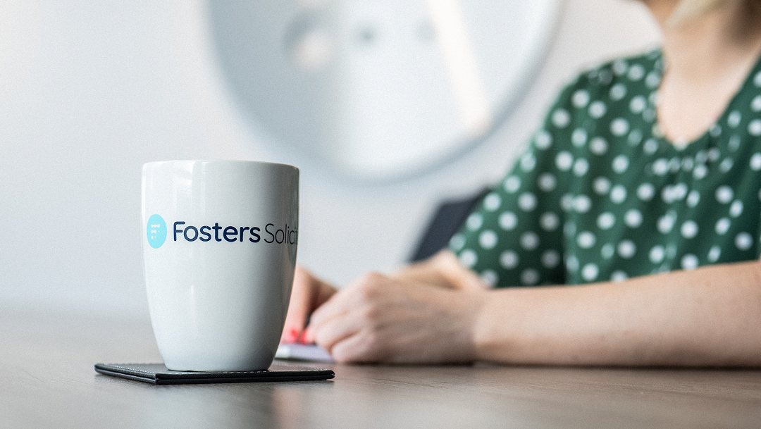 Fosters Solicitors mug on a table with a client in the background