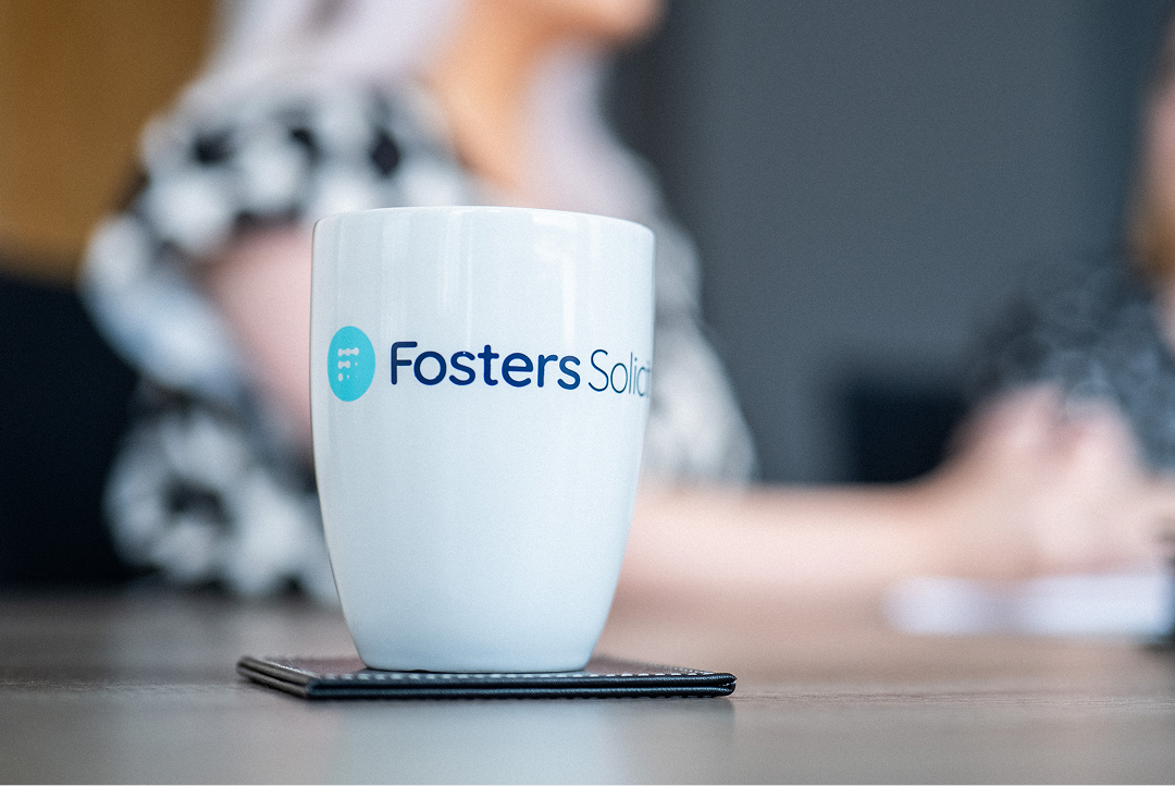 Fosters Solicitors mug on a table with a client in the background