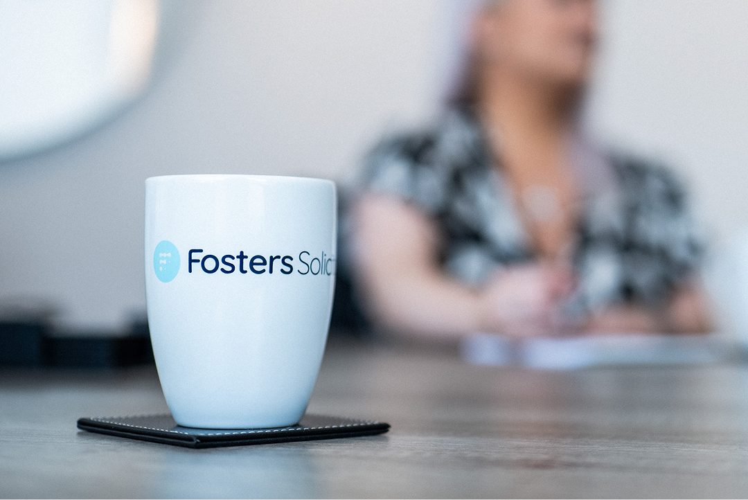 Fosters Solicitors mug on a table with a client in the background