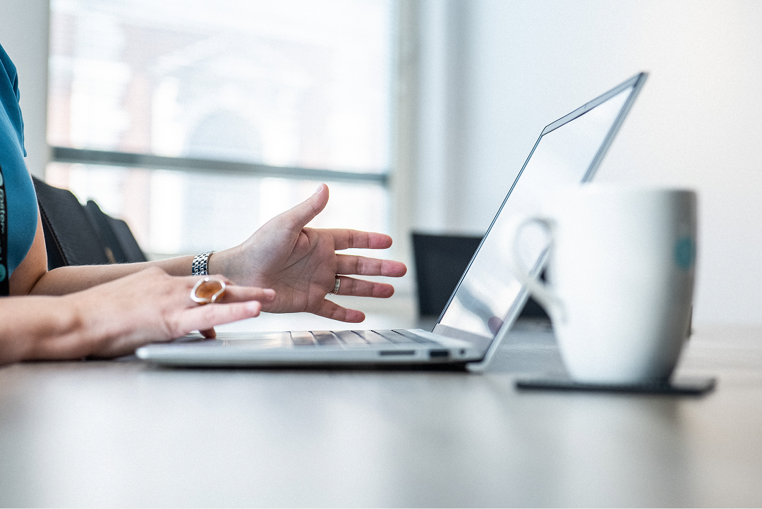 Client gesturing during a video call on a laptop at a desk