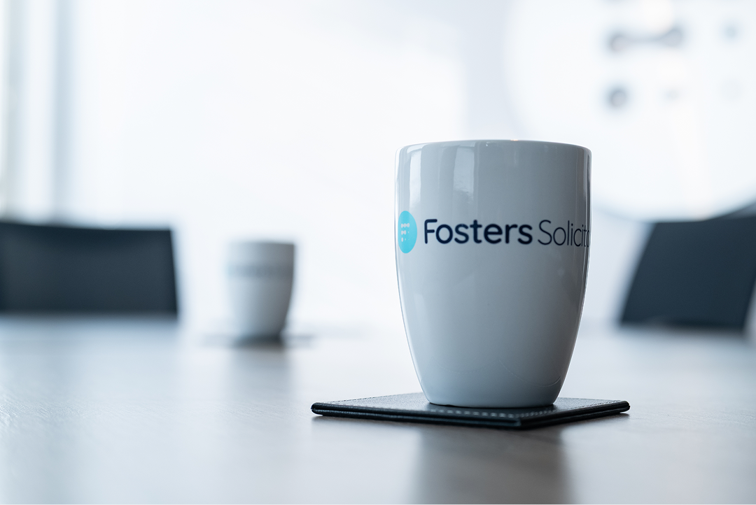 Fosters Solicitors mug on a boardroom table with empty chairs in the background