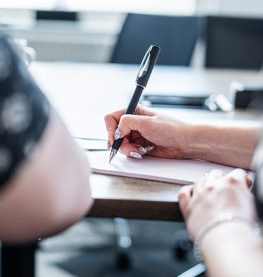 Close-up of a hand writing in a notebook at a desk