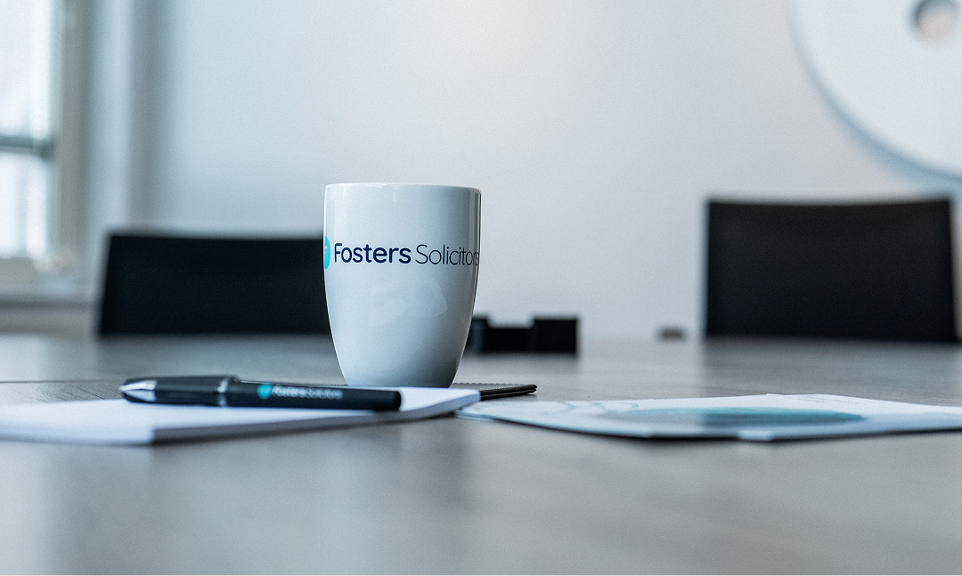 Fosters Solicitors mug and pen on a desk with papers