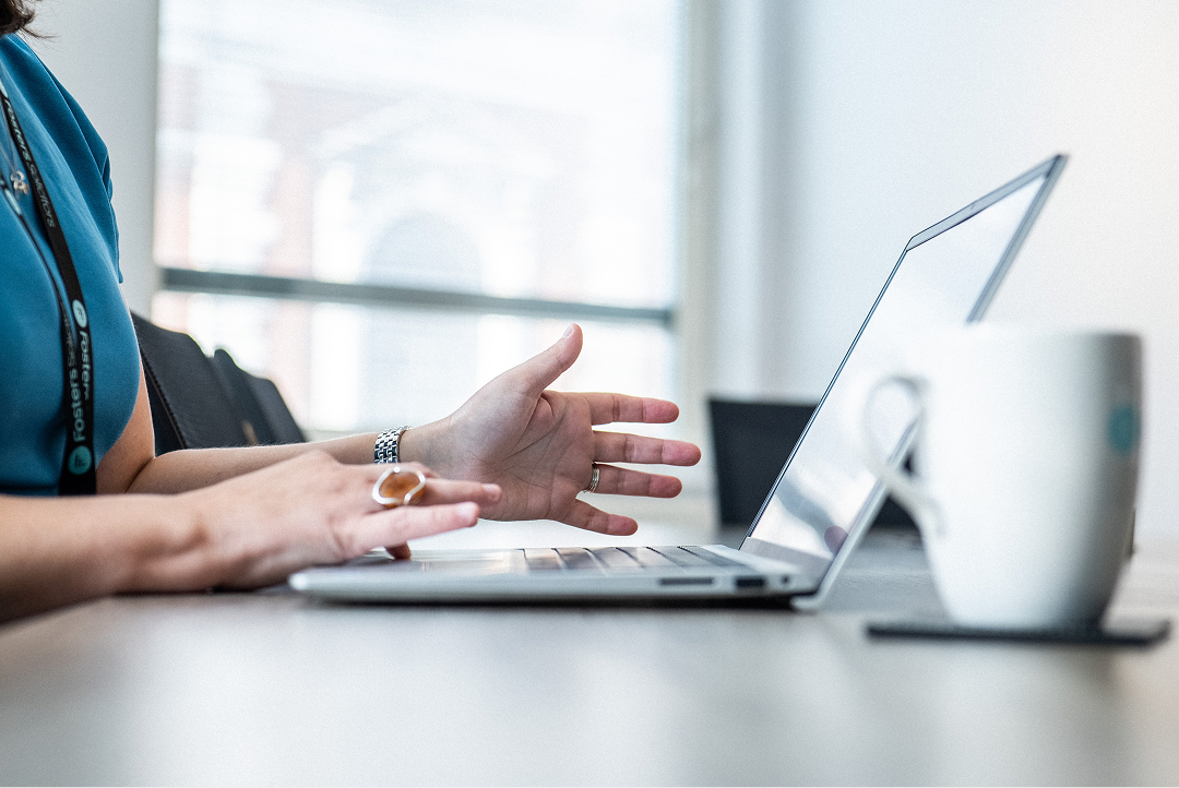 Client gesturing during a video call on a laptop at a desk