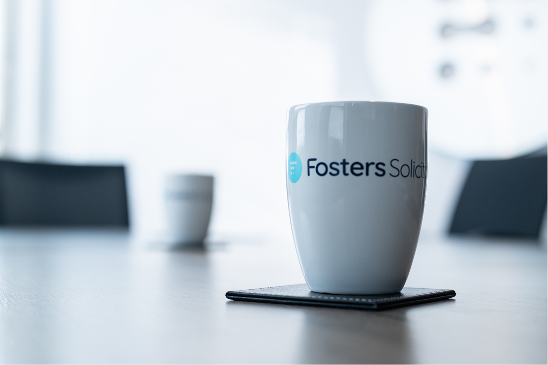 Fosters Solicitors mug on a boardroom table with empty chairs in the background