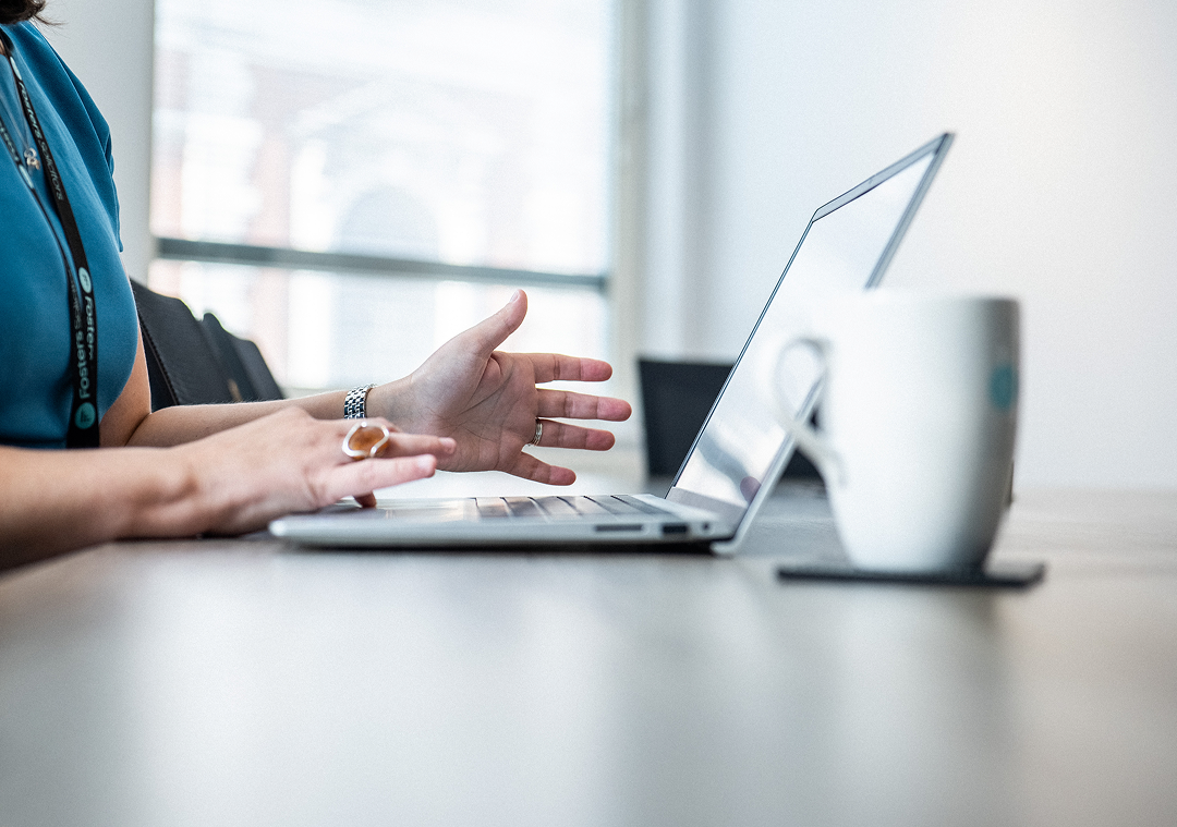 Client gesturing during a video call on a laptop at a desk