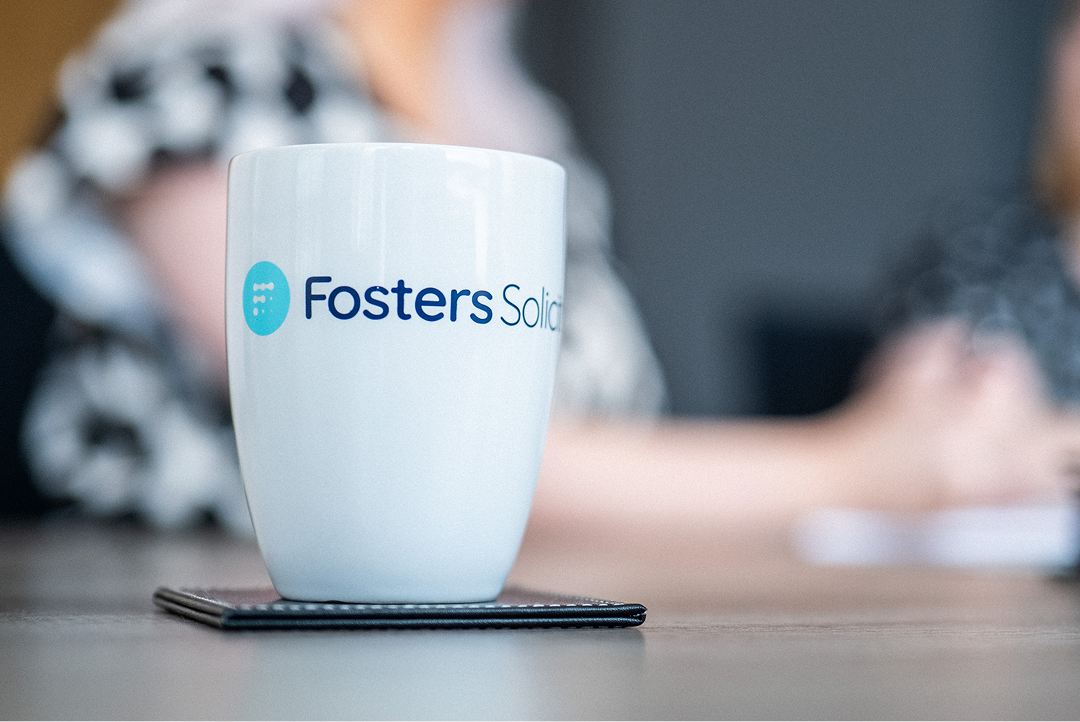 Fosters Solicitors mug on a table with a client in the background
