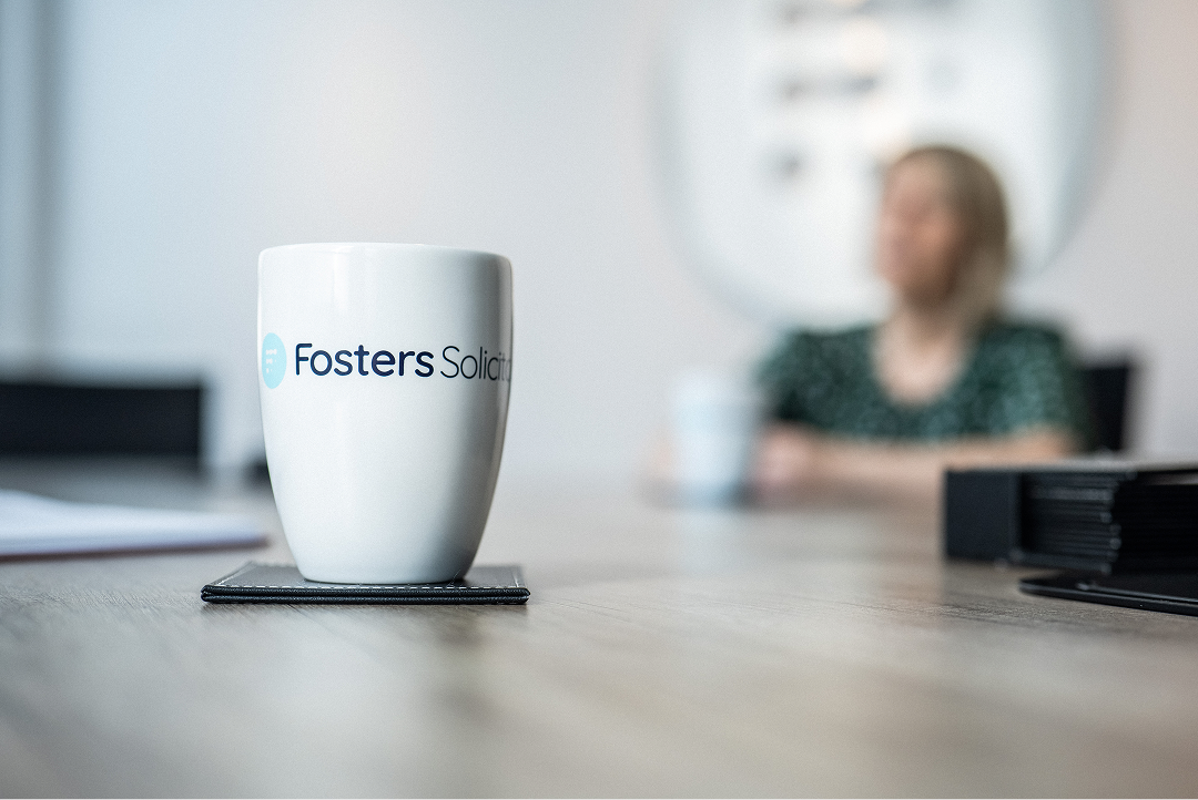 Fosters Solicitors mug on a table with a client in the background