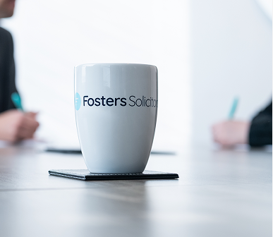 Fosters Solicitors mug on a table with clients in the background