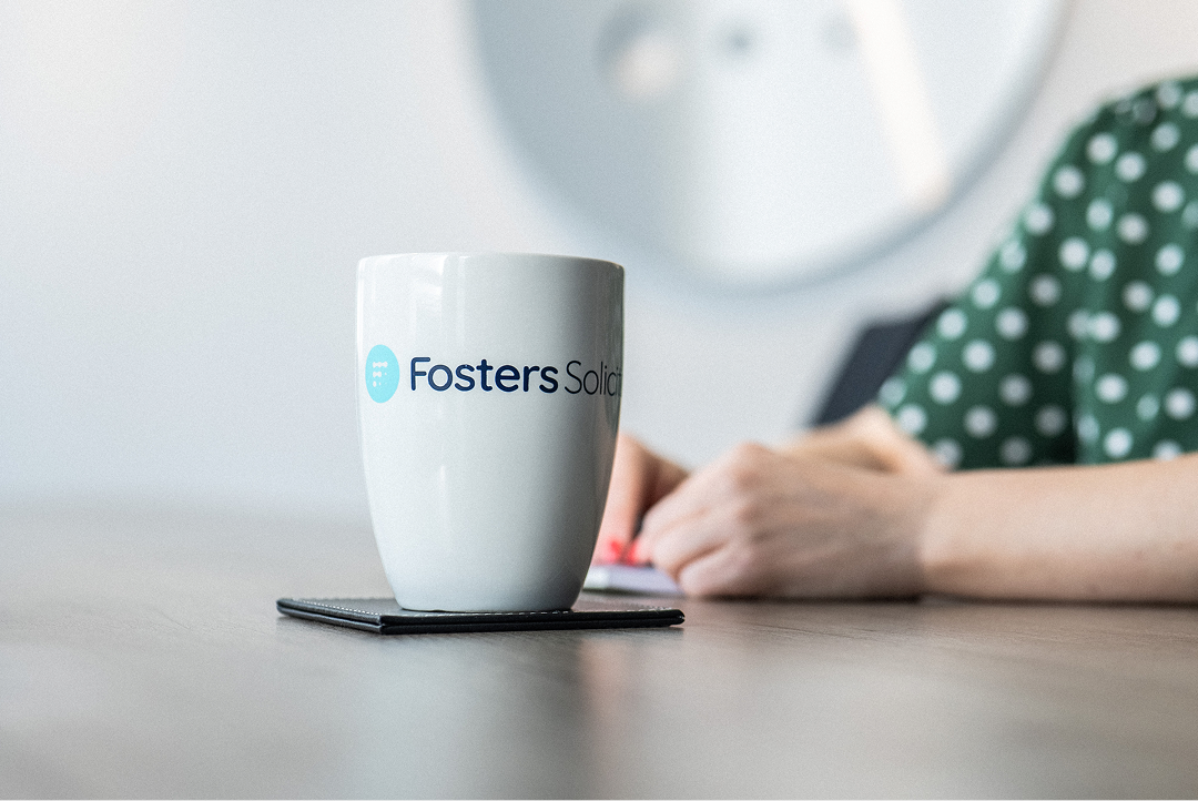 Fosters Solicitors mug on a table with a client in the background