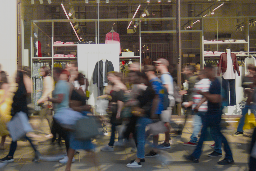 Blurred shoppers walking past a busy retail shopfront
