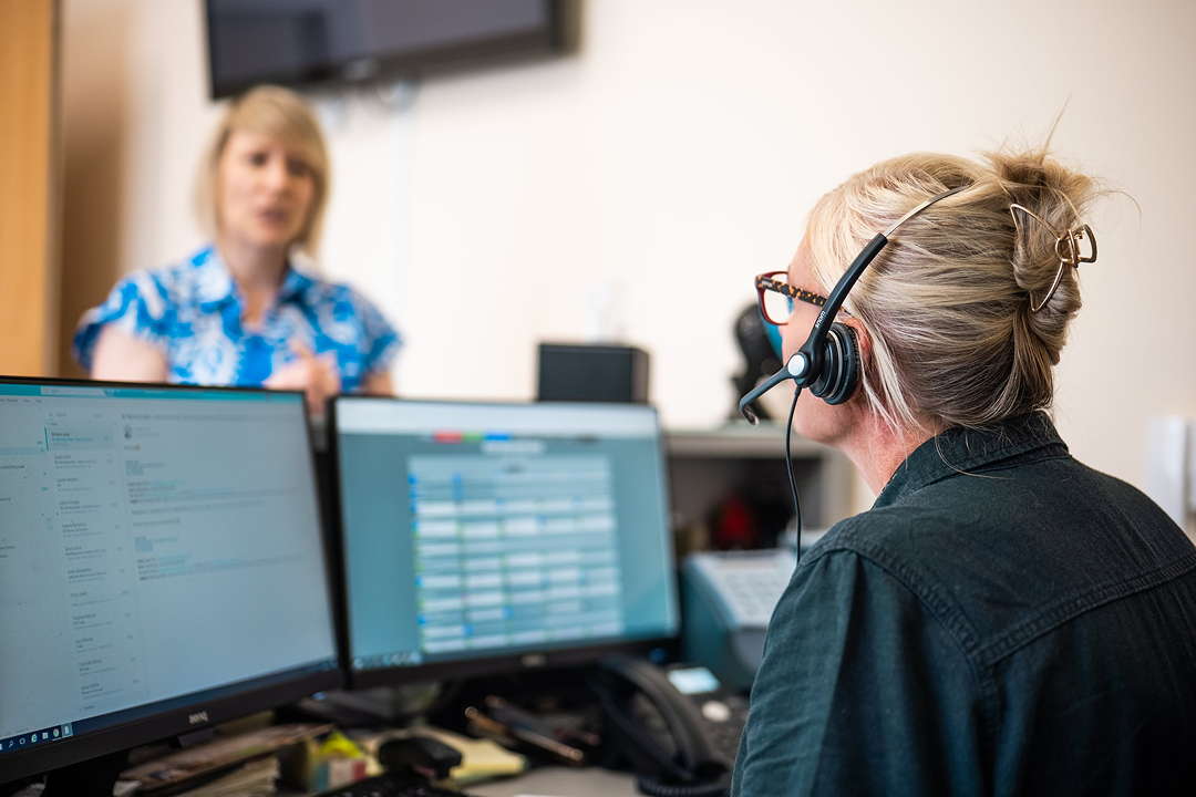 Fosters Solicitors adviser taking a call while a colleague looks on in the office