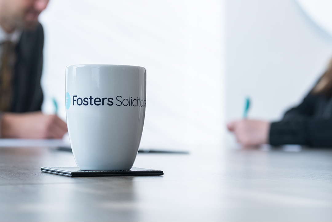 Fosters Solicitors mug on a boardroom table with colleagues writing notes