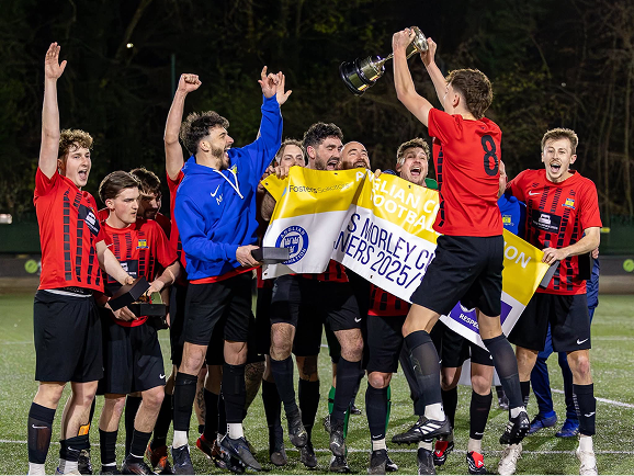 Local football team celebrating a league title win with a Fosters Solicitors sponsorship banner
