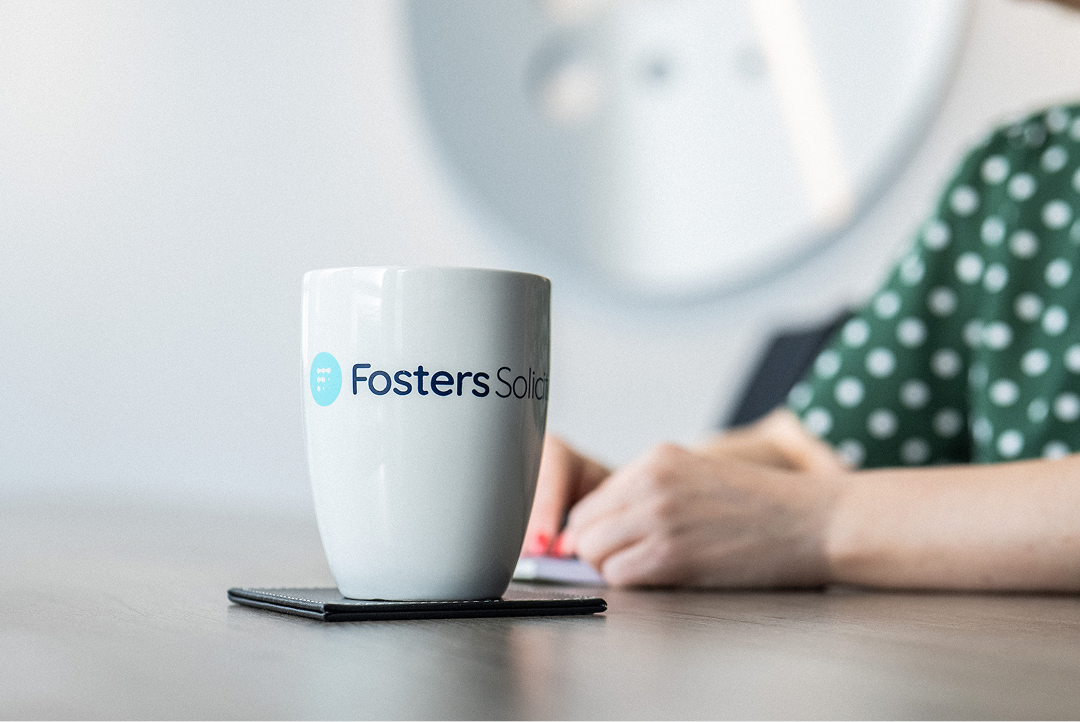 Fosters Solicitors mug on a table with a client in the background