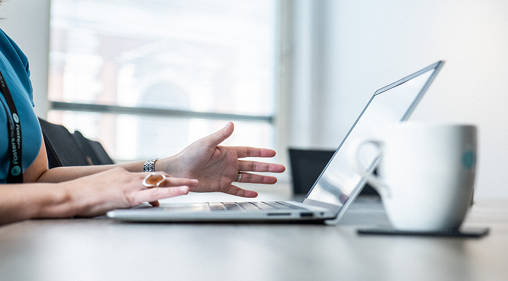 Client gesturing during a video call on a laptop at a desk