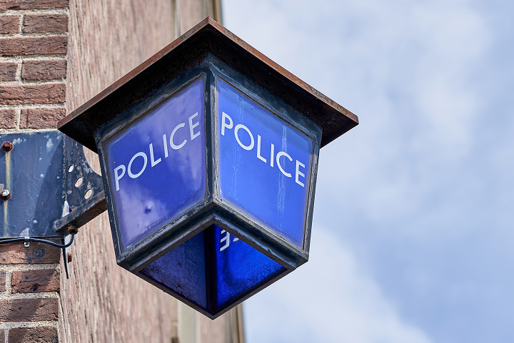 Traditional blue Police station lamp mounted on a brick wall