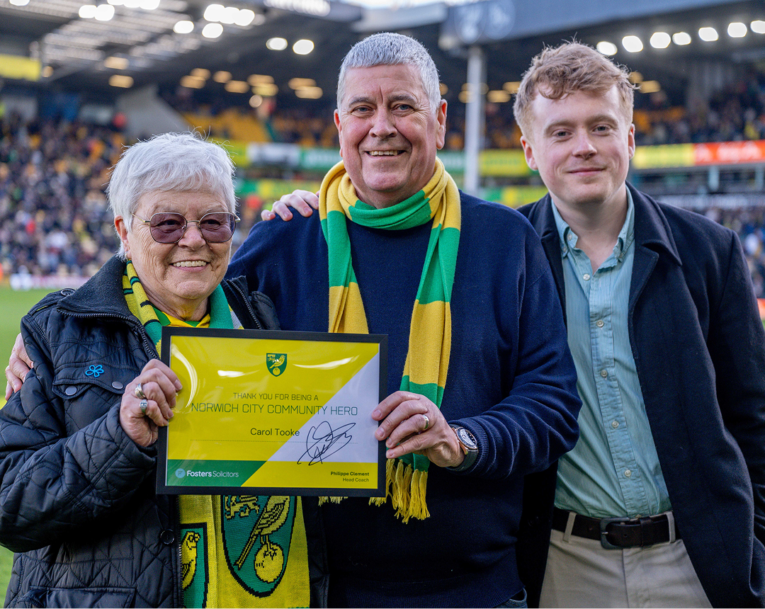 Fosters Solicitors presenting Carol Tooke with a Norwich City Community Hero award pitchside at Carrow Road