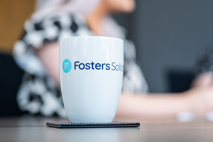 Fosters Solicitors mug on a table with a client in the background
